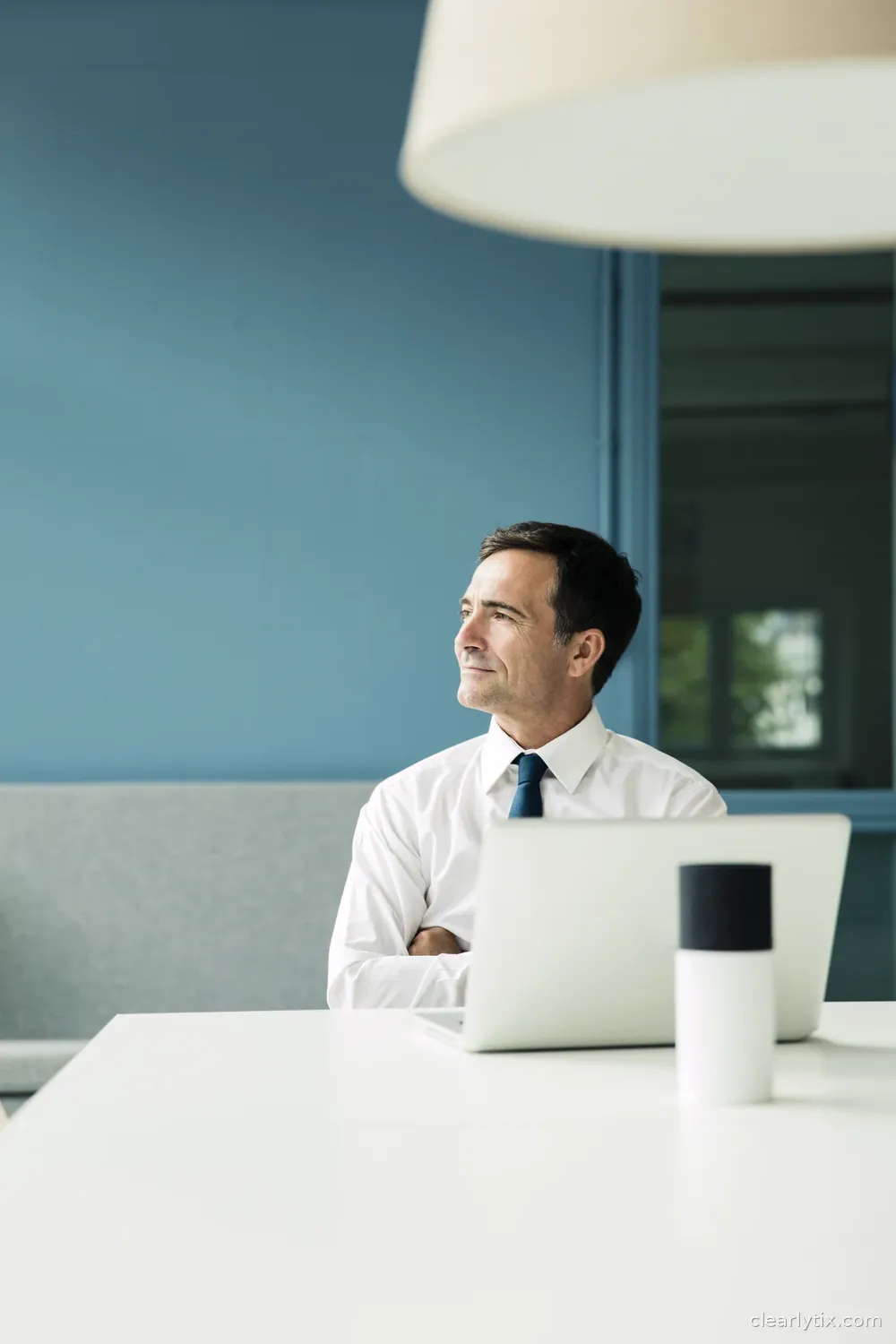 A man leans back from his laptop in an office, thinking about what his numbers mean.