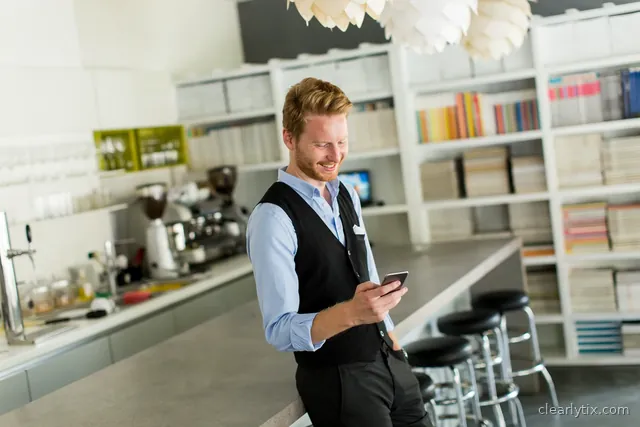 An agency professional smiling at his phone in a modern workplace.